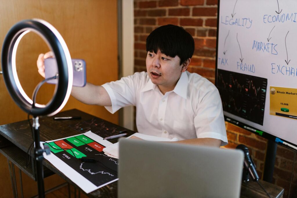 a man creating social media content at home with his phone and a ring light.