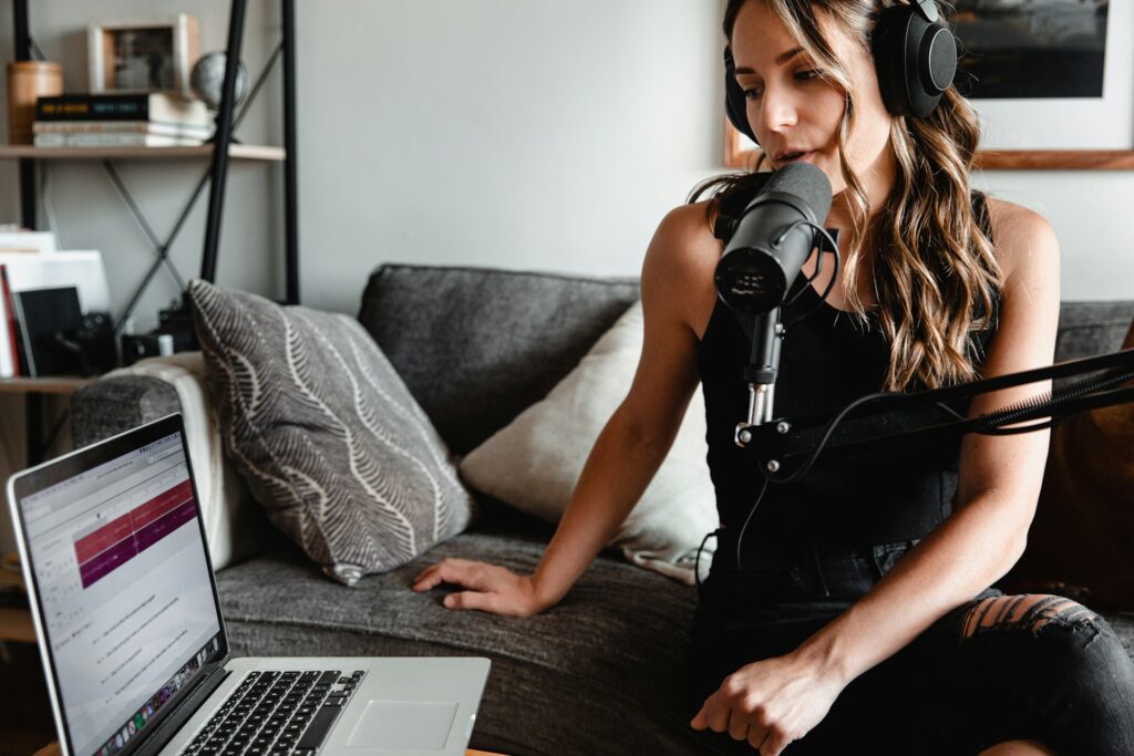 a woman recording a podcast on her phone and laptop